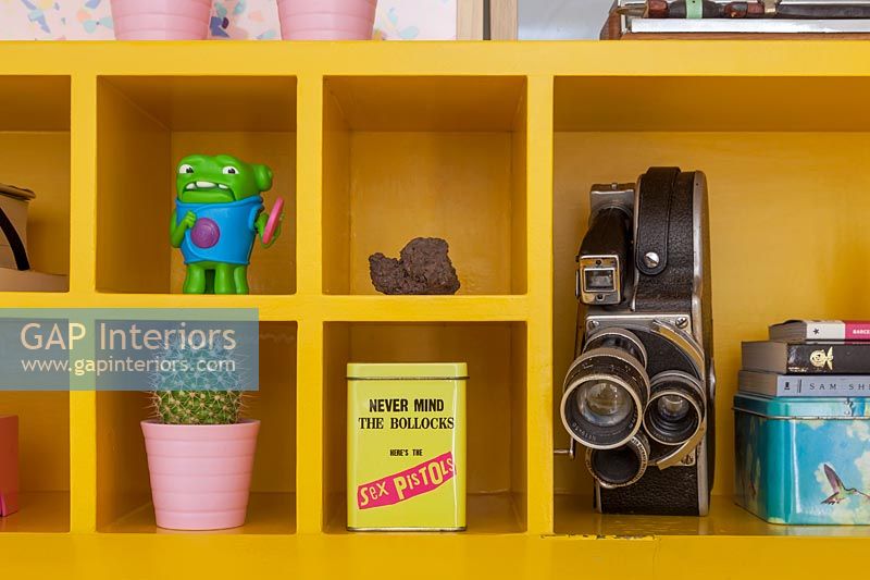 Vintage cine camera and ornaments on bright yellow shelves