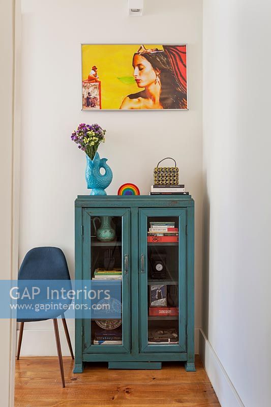 Blue painted cabinet and colourful artwork 