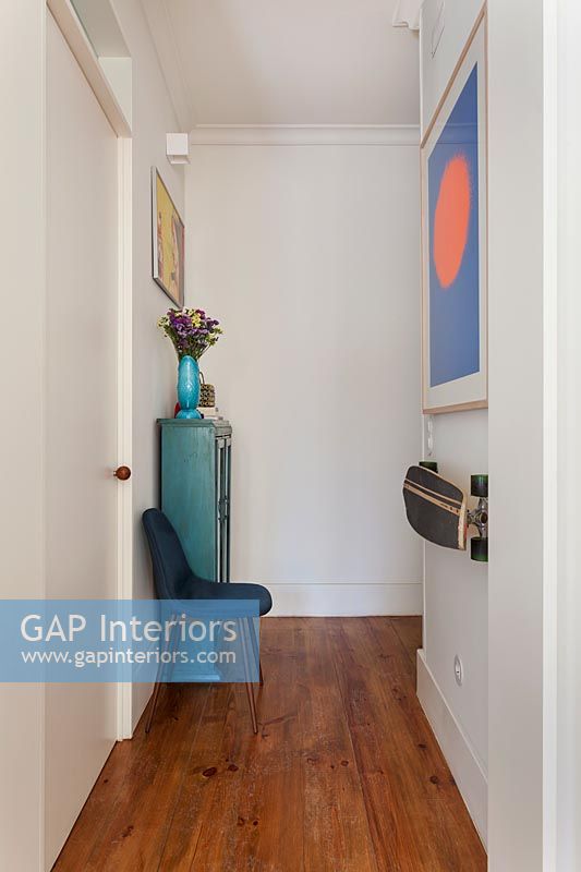 Blue painted cabinet and colourful artwork in hallway 
