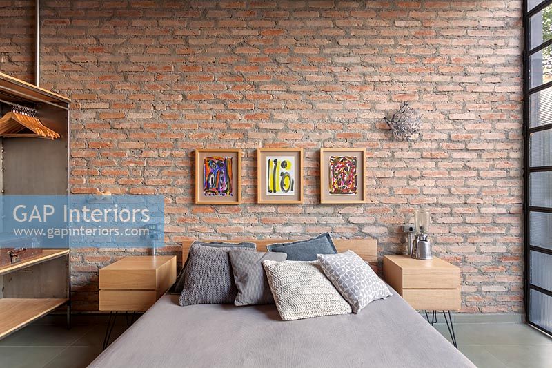 Modern industrial bedroom with exposed brickwork wall 