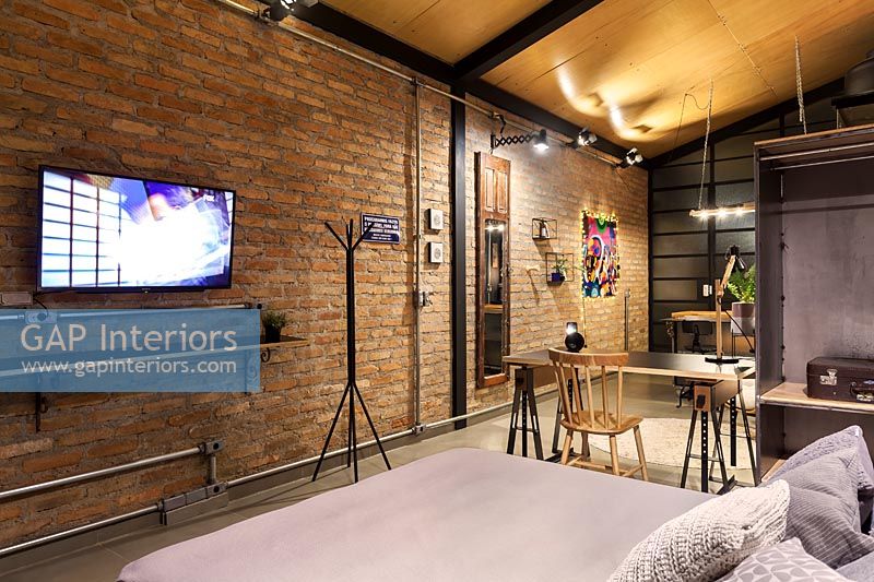 Modern industrial bedroom with wall mounted television in open plan apartment
