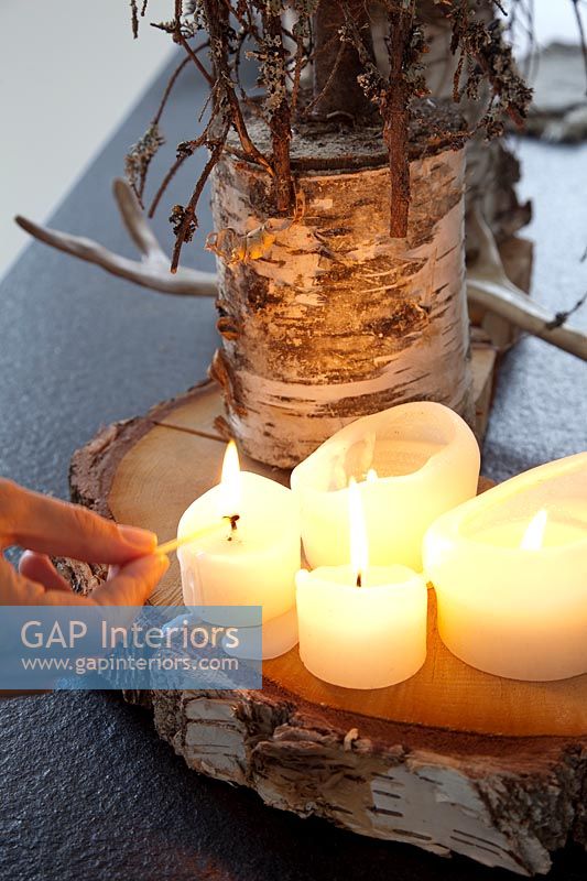 Hand lighting candles on natural wooden base 