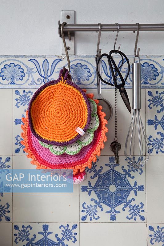 Crochet heat pads and utensils on hooks in kitchen  