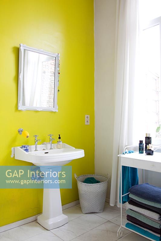 Bright yellow painted feature wall behind bathroom sink 