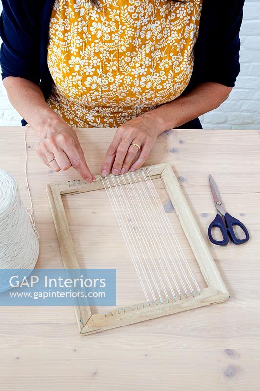Crafting accessories on table - woman attaching thread to wooden picture frame
