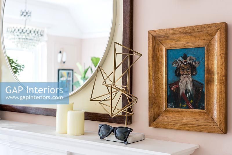 Framed painting, mirror and metal sculpture over fireplace 
