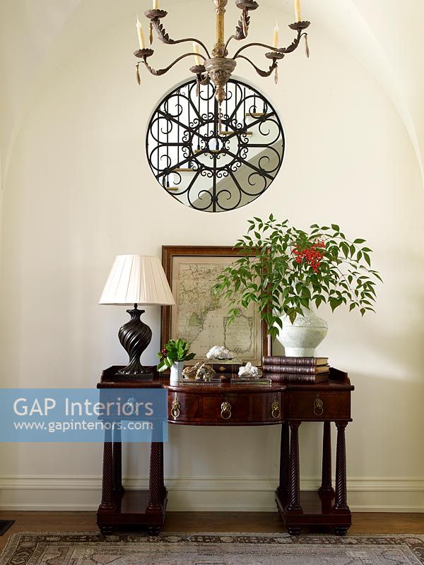 Decorative grate on circular internal window above console table 