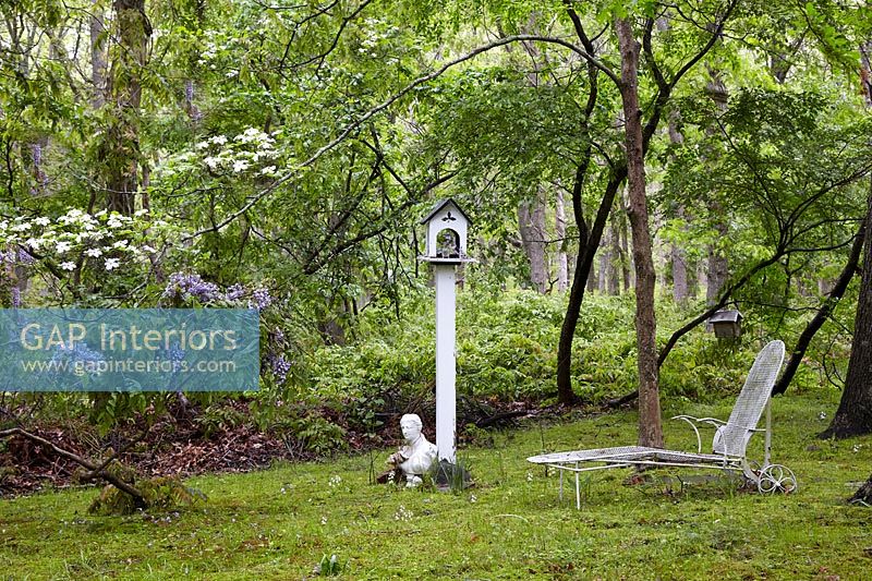 Bird table and recliner in woodland garden 