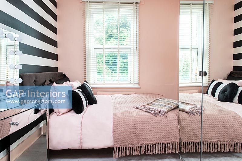 Pink bedroom with black and white striped wall  