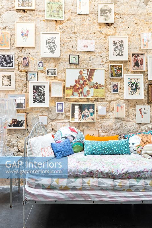 Large stone wall filled with pictures over daybed in childrens room 