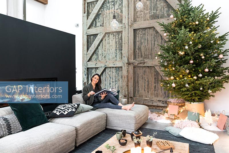 Woman relaxing in modern country living room decorated for Christmas 