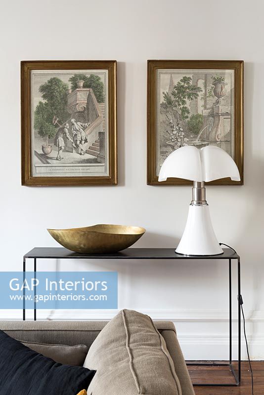 Framed paintings over side table with modern lamp 