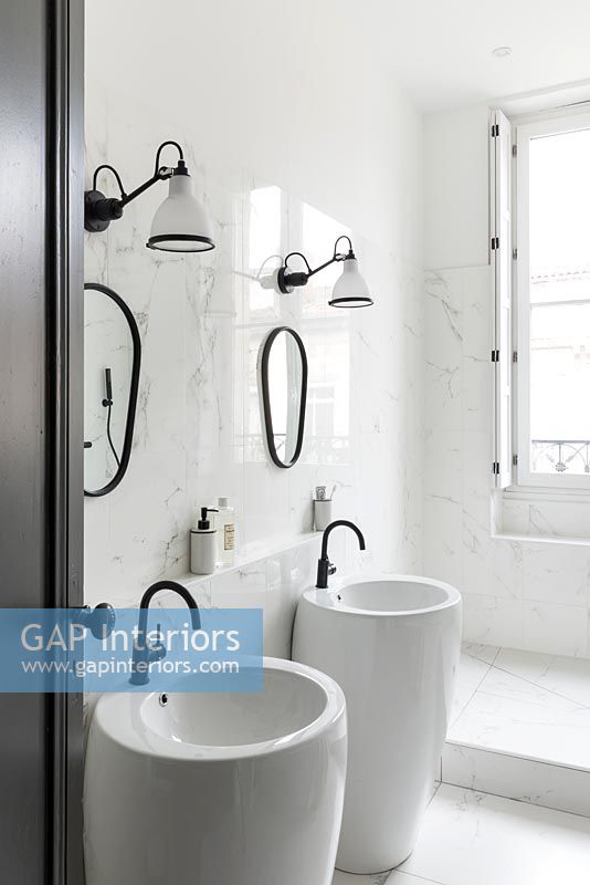 Double sinks in modern white bathroom with black taps and mirror frames 