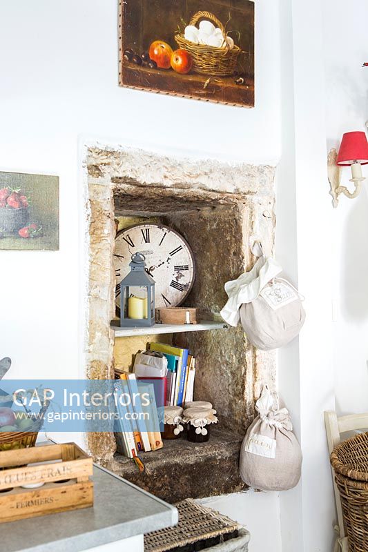Stone alcove with recipe books on shelves in rustic kitchen 