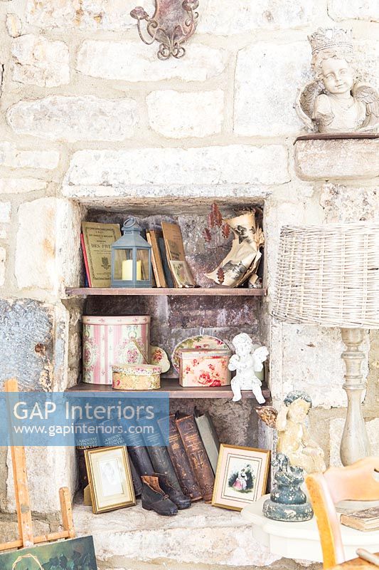 Stone wall alcove shelves with display of books and ornaments 
