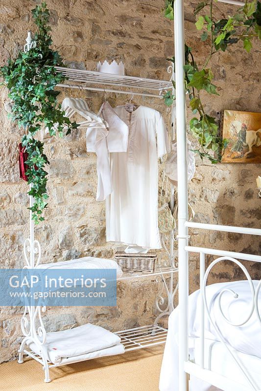 White metal clothes rail with natural garlands and exposed stone wall 