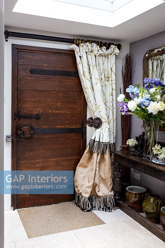 Wooden front door with curtain in country hallway 