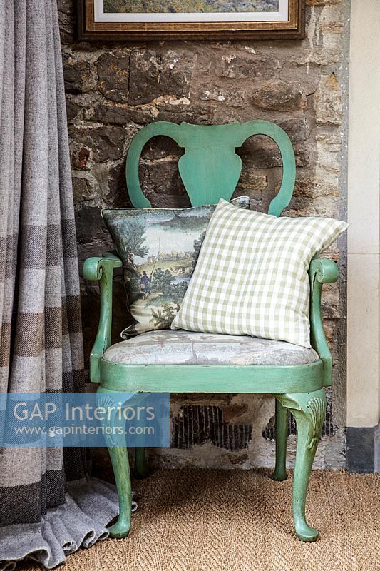 Mint green painted wooden chair against stone wall 