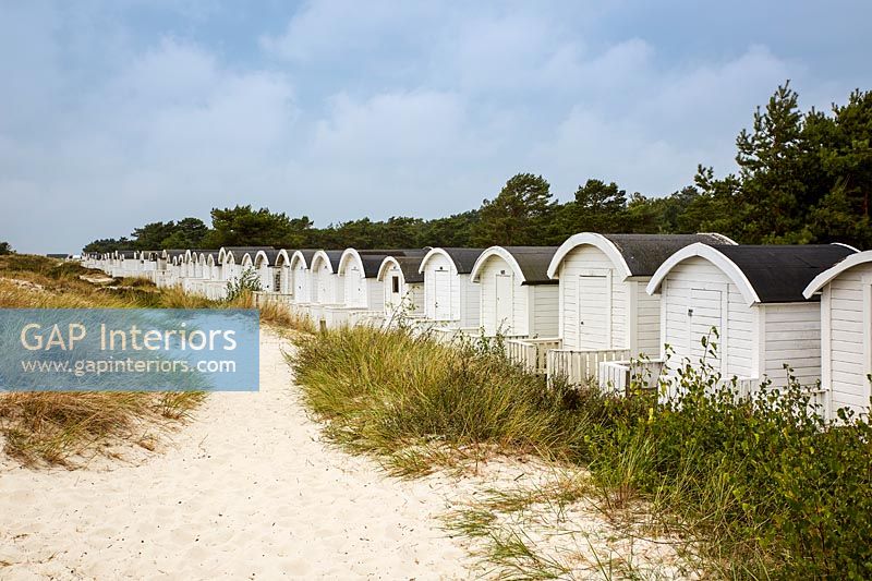 Tiny white wooden cabins along coastal shoreline 