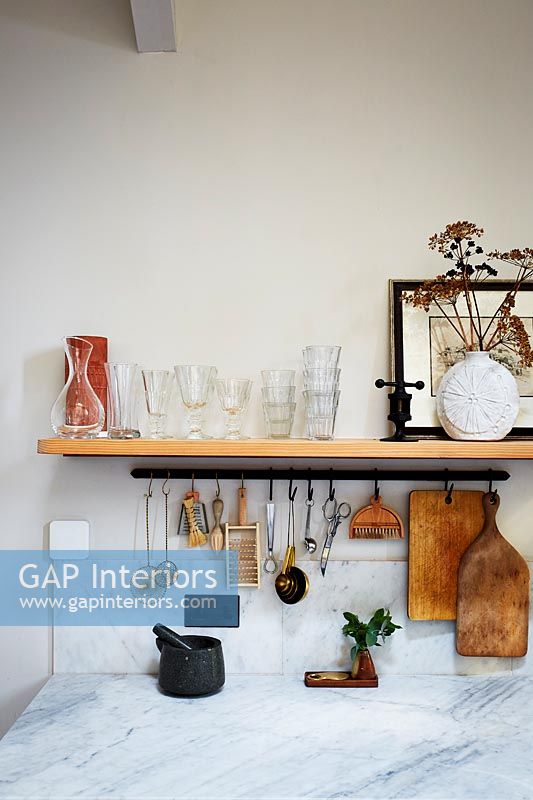Marble worktop and wooden shelf with utensils in modern kitchen 