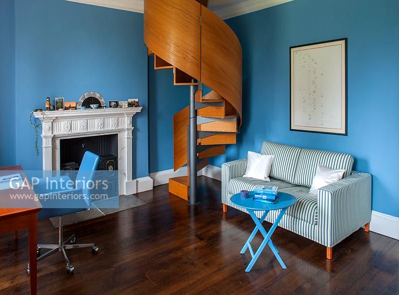 Brushed steel spiral staircase in blue study with fireplace 