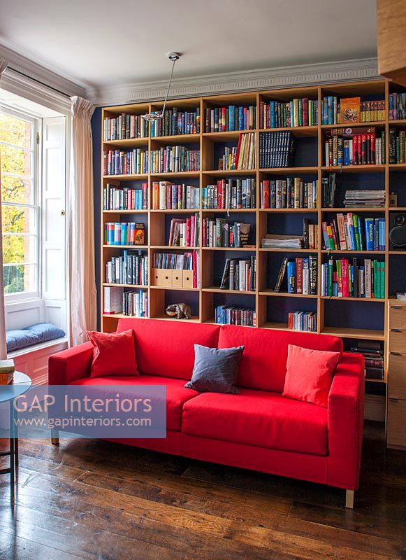 Wall of bookshelves and red sofa 