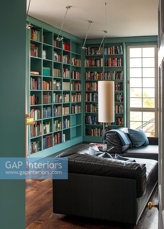 Black leather sofa in library with painted bookshelves 