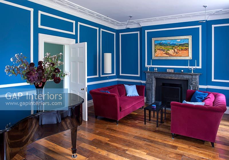 Azure blue painted living room with pink velvet sofas 