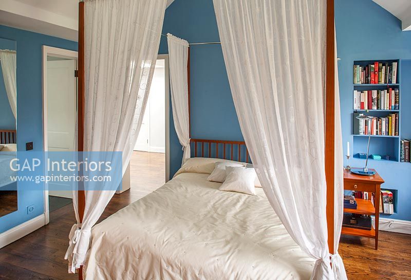 White four poster bed in blue and white bedroom 