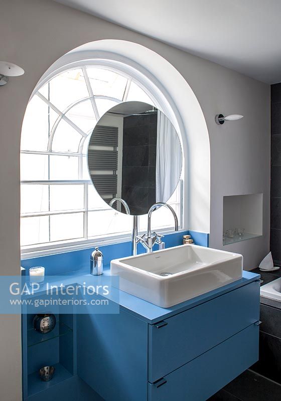 Blue and white bathroom with arched window 