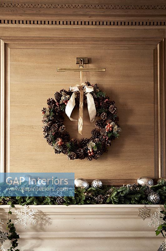 Christmas wreath on wooden paneled wall above fireplace 