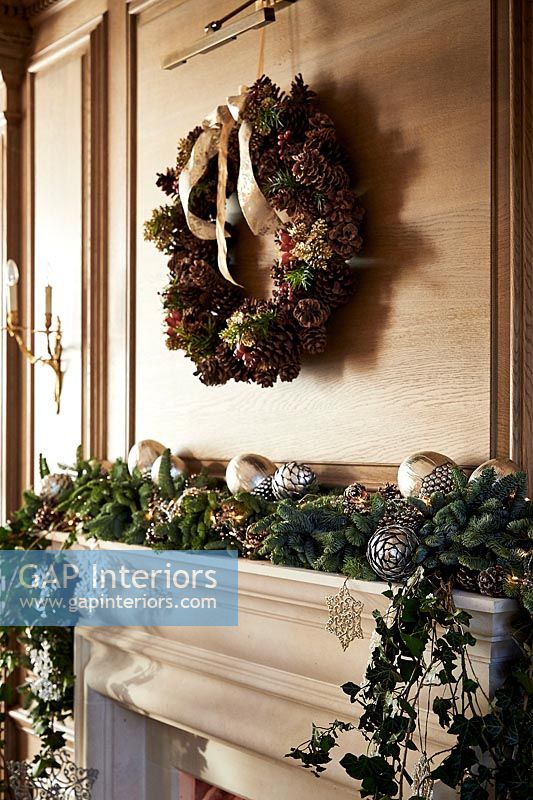 Christmas wreath on wooden paneled wall above fireplace 