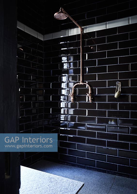 Shower with black brick style tiling and copper shower head 