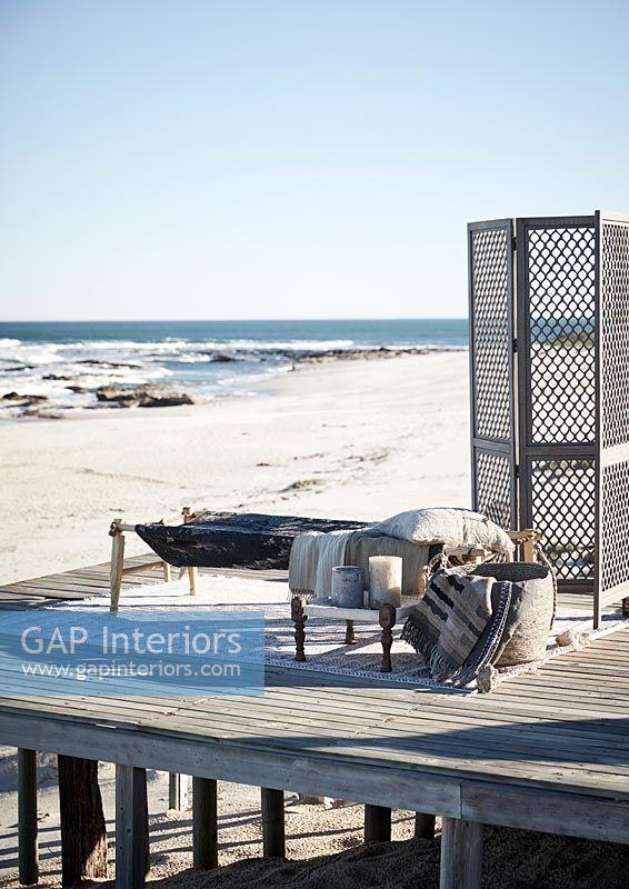 Wooden platform with bed and folding screen on beach 