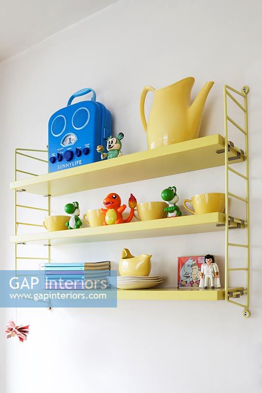 Yellow shelves with childrens toys and crockery 