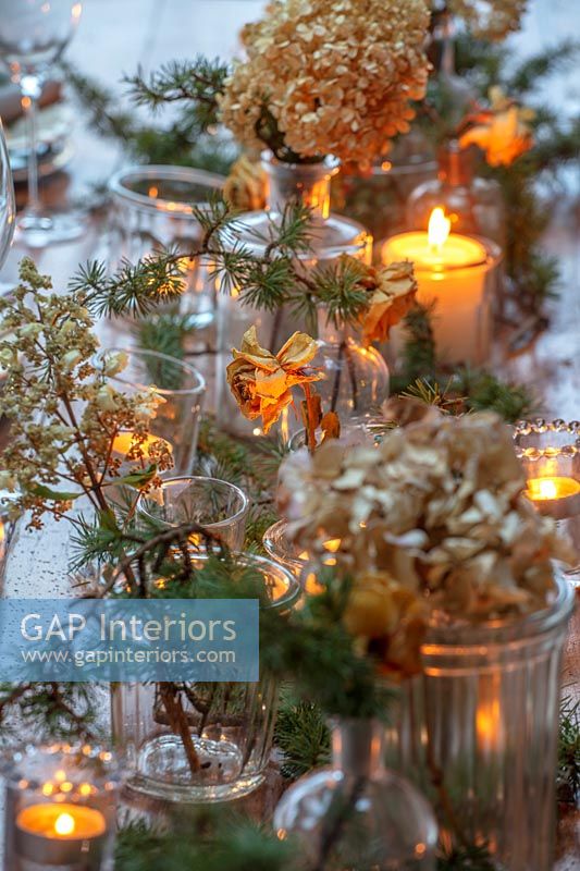 Dried flowers in vases on Christmas dining table with candles 