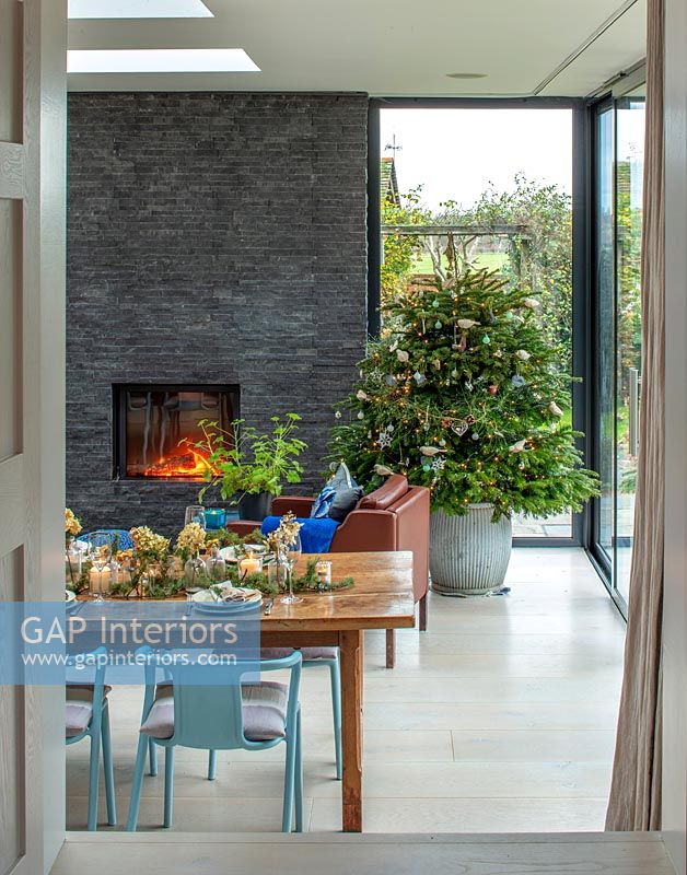Christmas tree in modern dining room with lit fireplace 