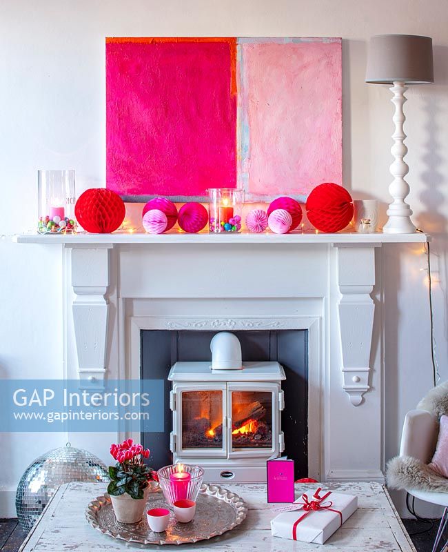 Modern artwork and paper baubles on mantelpiece 