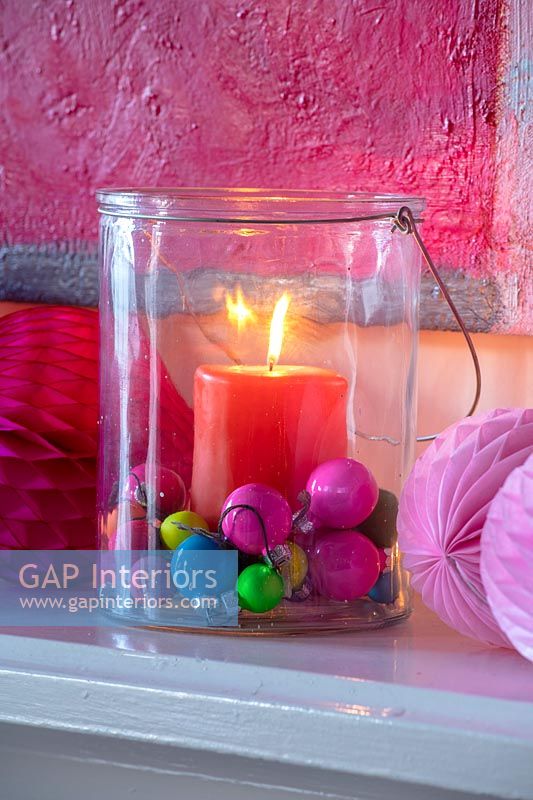 Candle in glass jar with colourful decorations 