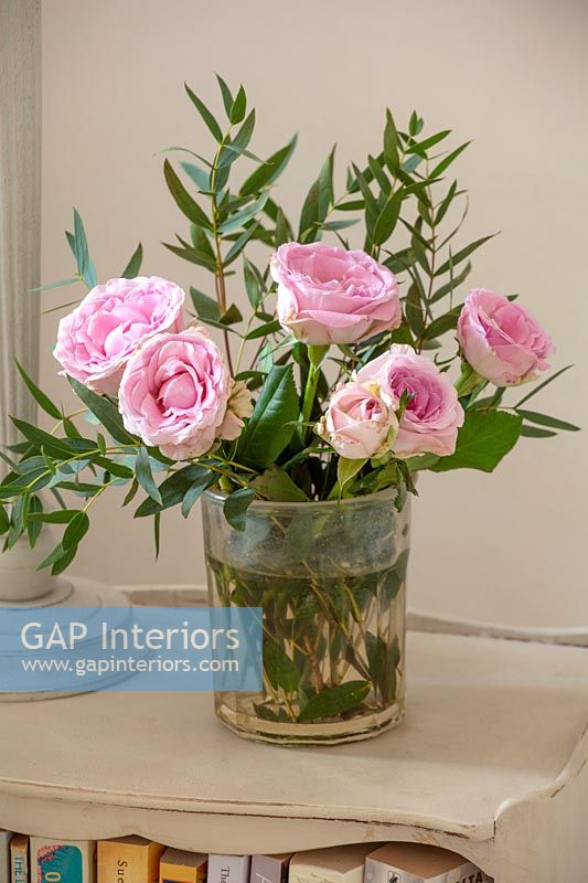 Pink roses in vase on bedside table 