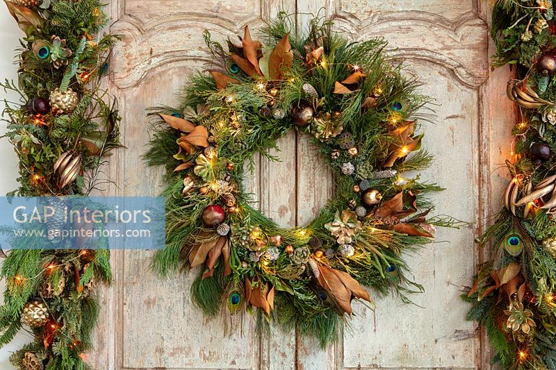 Christmas wreath and garland with fairy lights on double wooden doors 