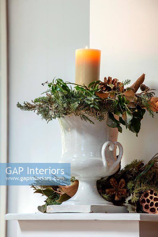 White urn with Christmas decorations and candle