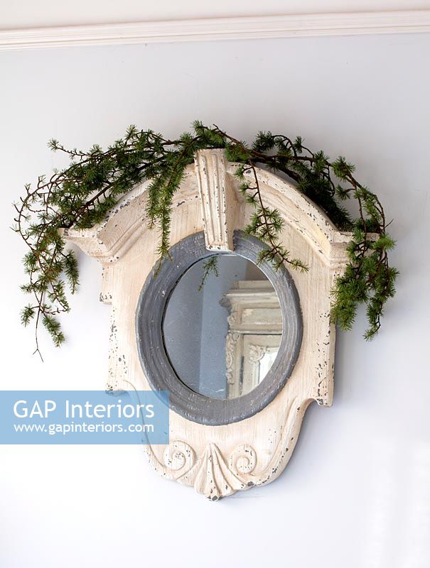 Wall mounted plaster mirror with sprig of foliage as decoration 