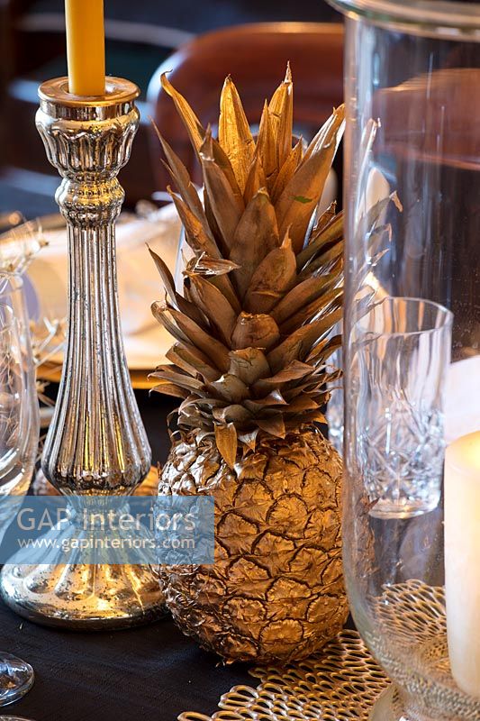 Gold sprayed pineapple and silverware on classic dining table 