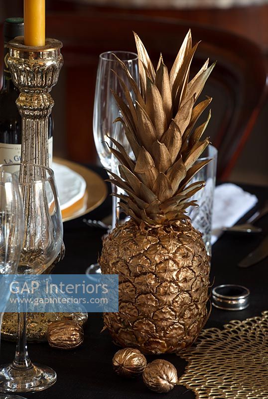 Gold sprayed pineapple and walnuts on classic dining table 