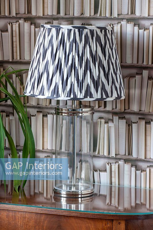 Bookcase wallpaper and black and white lampshade on glass lamp 