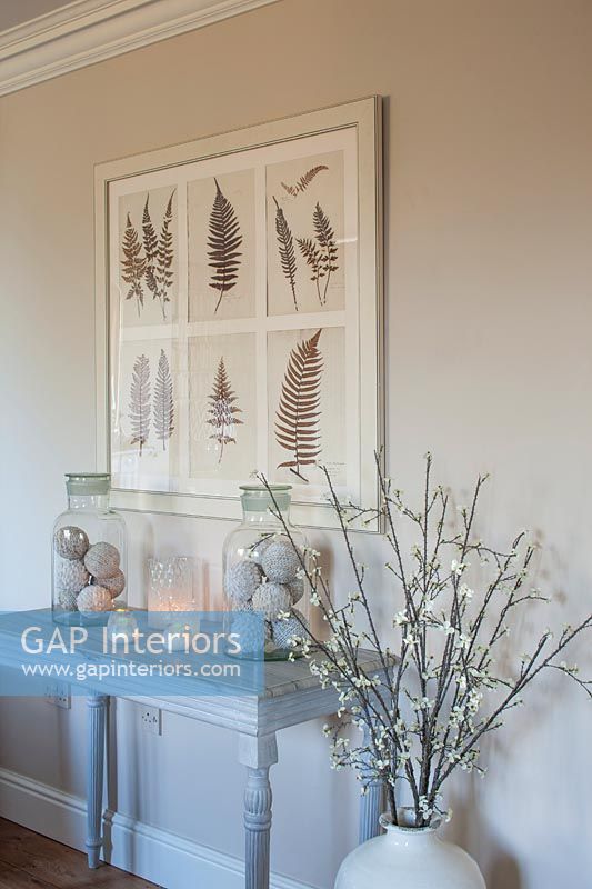 Painting of ferns on wall above side table 
