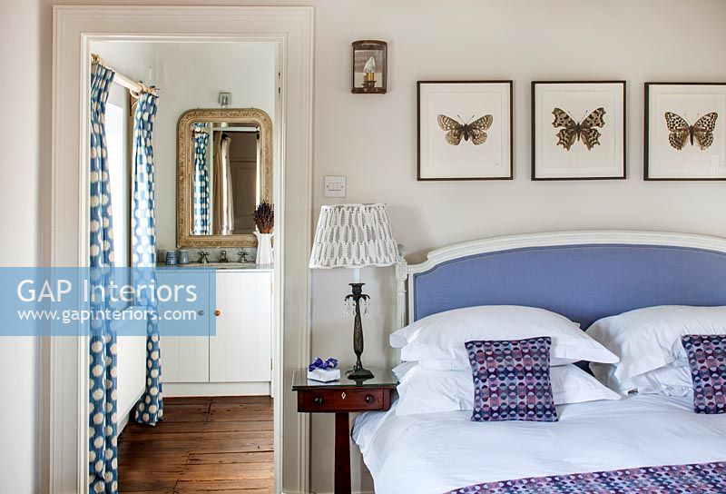 Butterfly paintings above lilac bed in classic bedroom 
