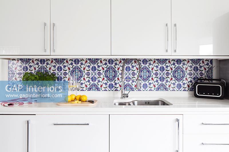 Modern white kitchen with patterned blue tiled splash-back 