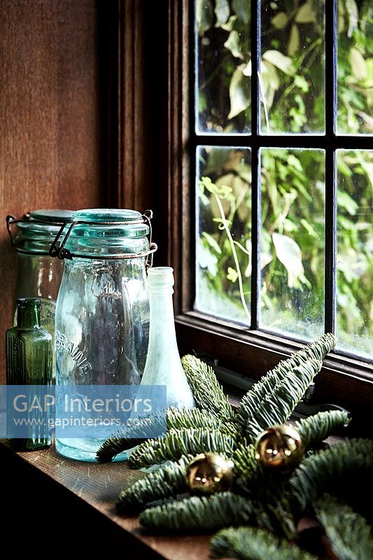 Glass jars and Christmas decorations on windowsill 